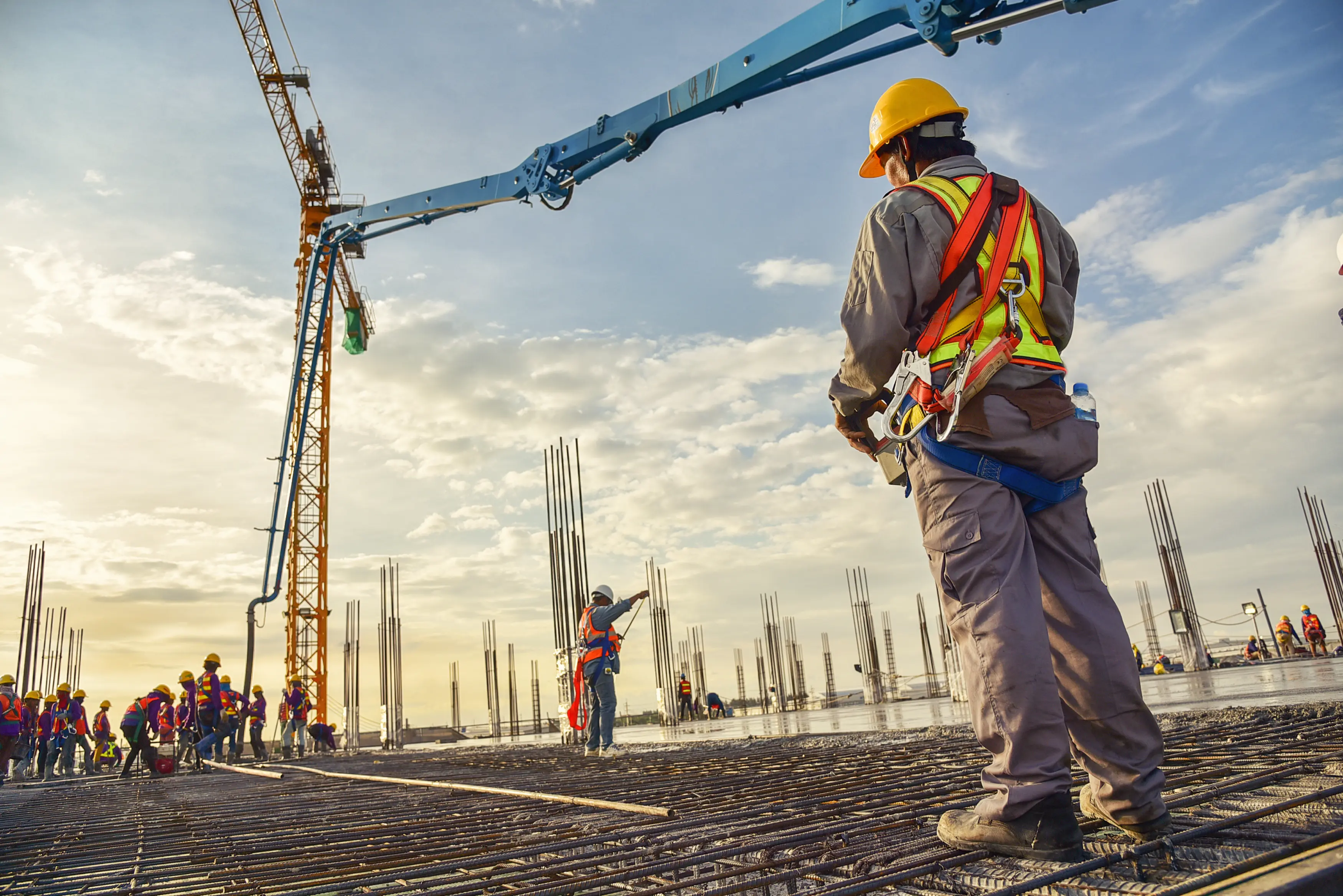 Construction workers at a building site with cranes and concrete structures